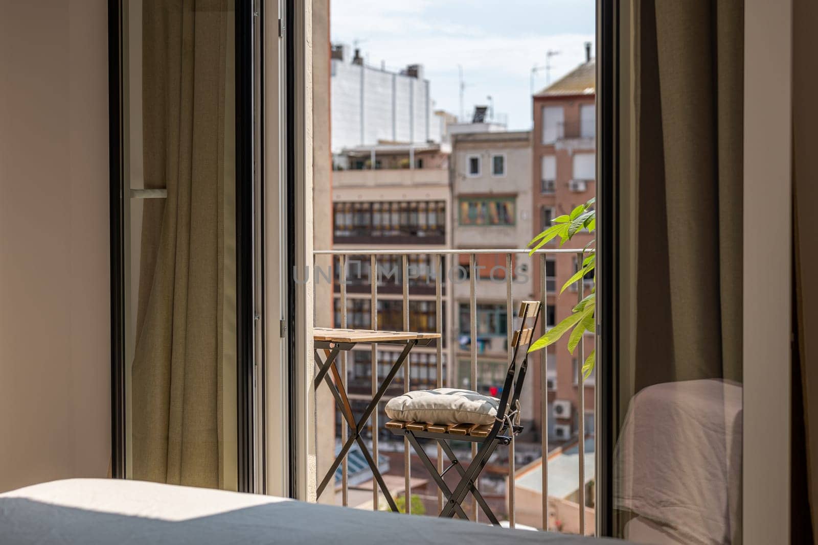 Small table and chair on sunny terrace view from renovated apartment. Simple place to rest on open balcony in residence in Barcelona city