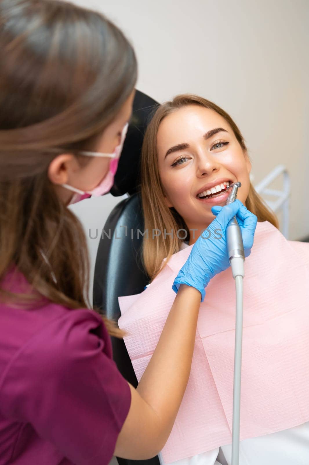Attractive young woman having a professional brushing of teeth in stomatology clinic.