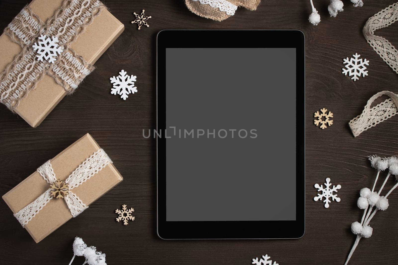Tablet with a blank screen surrounded by Christmas decorations and gifts, mocap for advertising by galsand
