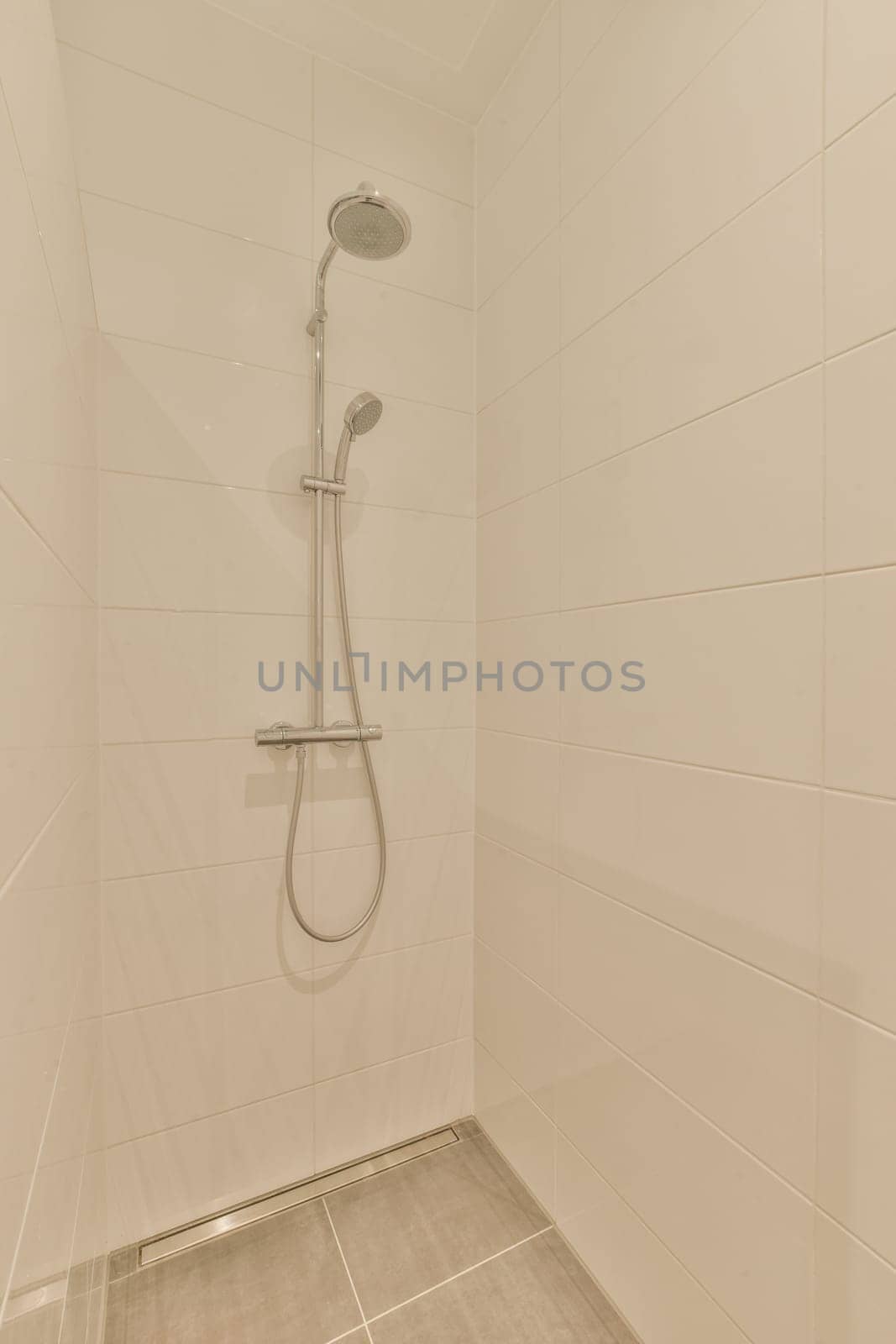 a white shower in a white tiled bathroom by casamedia