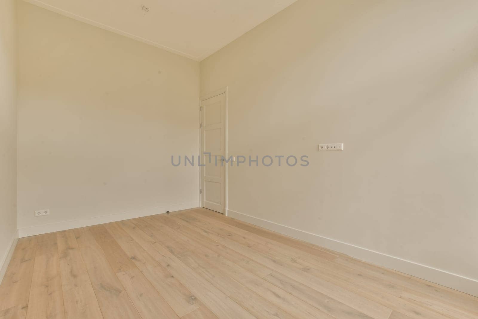 an empty room with white walls and wood flooring on the right, there is a door in the corner