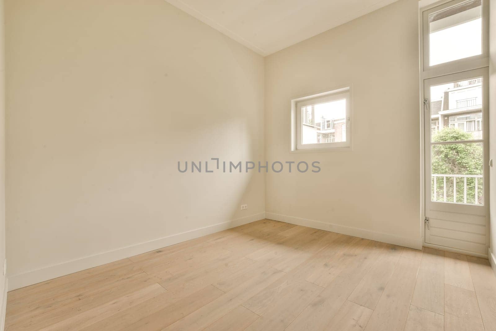an empty room with white walls and wood flooring on the right side, there is a window in the corner