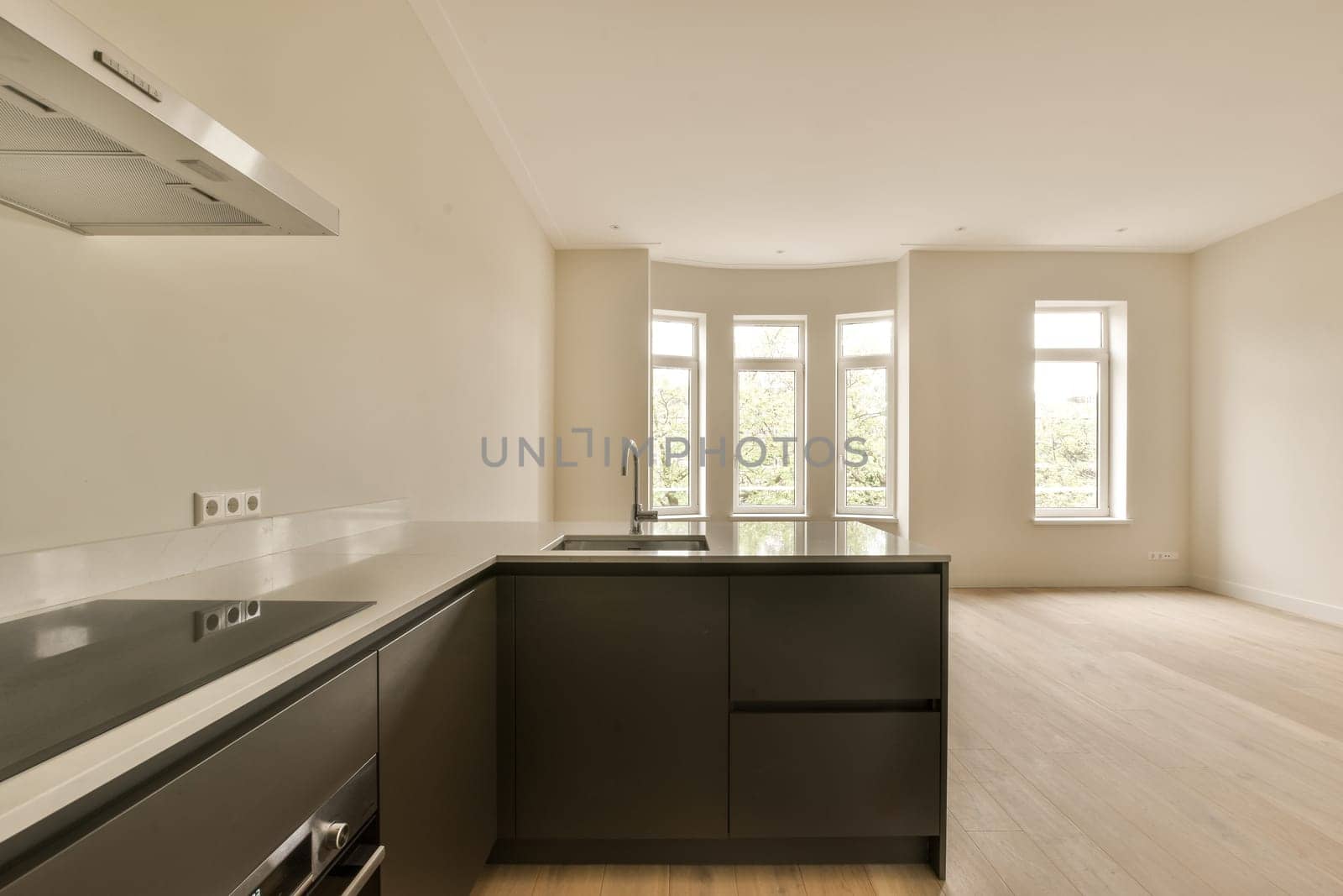 an empty kitchen with black cabinets and a large window by casamedia