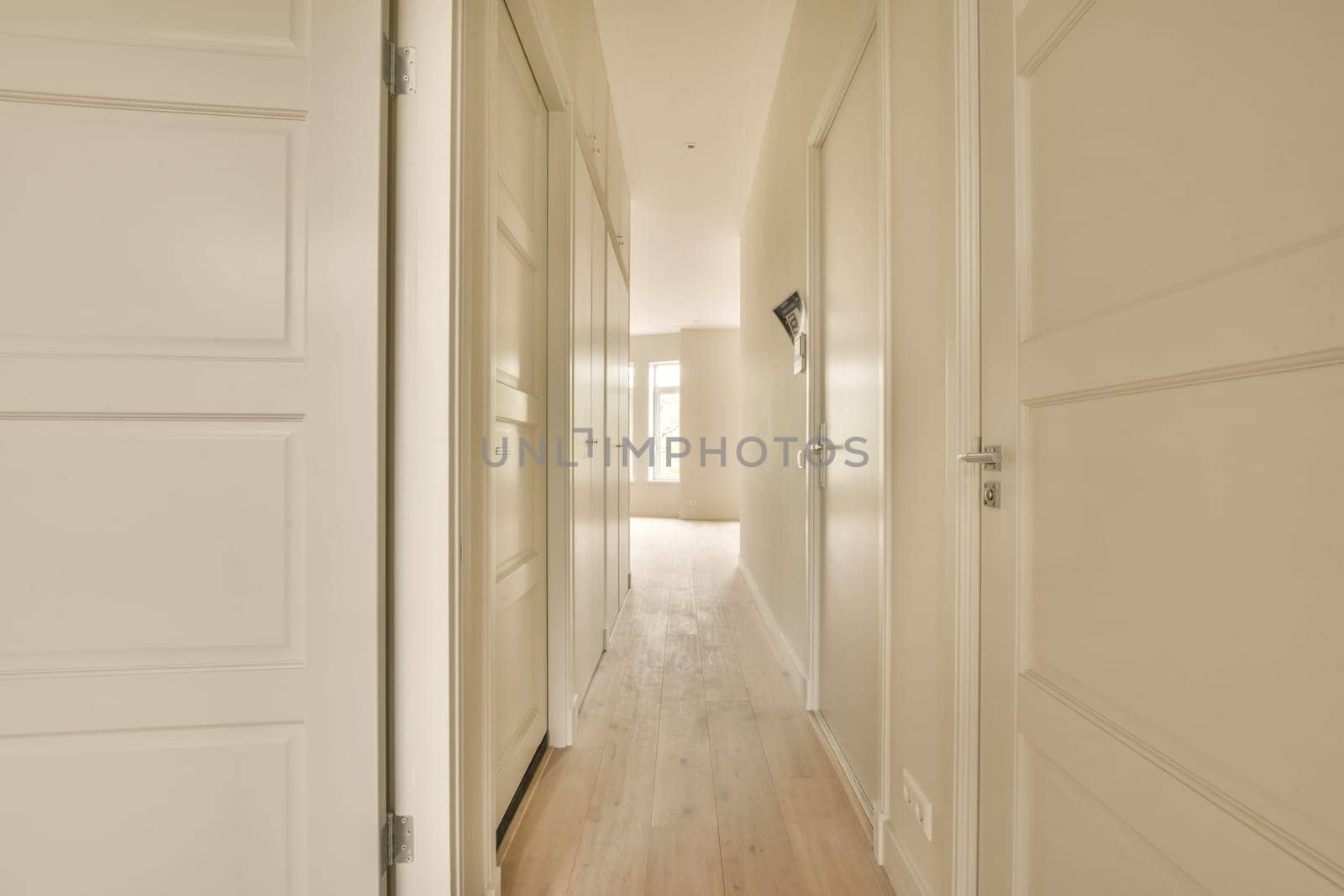 a hallway with white wood floors and white doors by casamedia