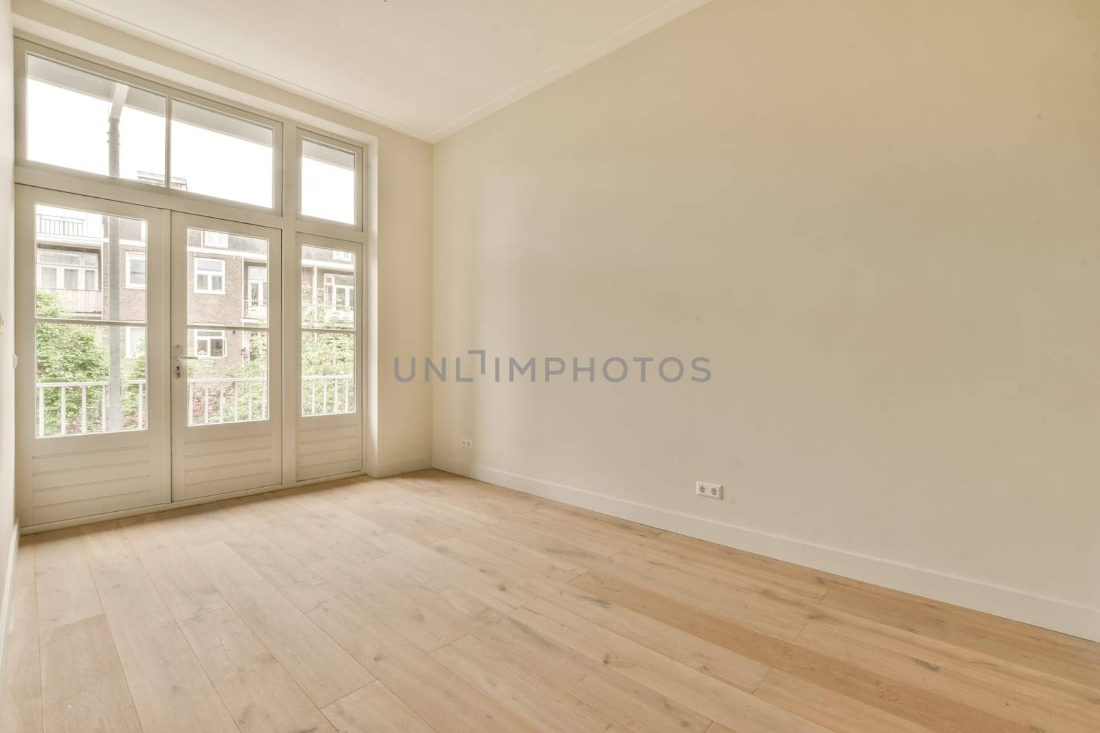 an empty room with white walls and wood flooring in front of the door that leads out to a balcony