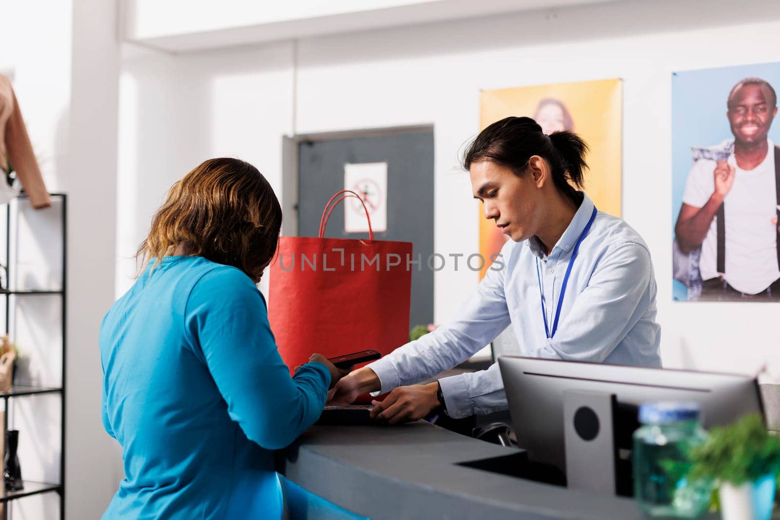 African american customer paying for clothes at counter desk in clothing store, putting credit card on pos. Shopaholic woman shopping for casual wear in modern botique. Fashion concept