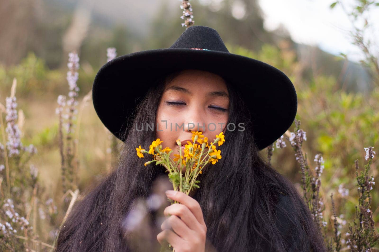 young woman in love smelling her lover's yellow flowers with her eyes closed surrounded by wildflowers. valentine days. High quality photo