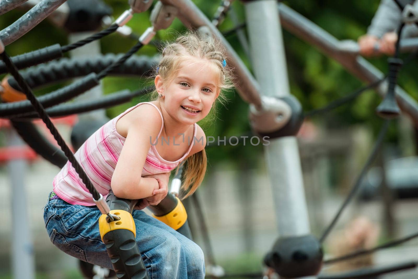 Happy cute smiling little girl playing at the playground outdoor
