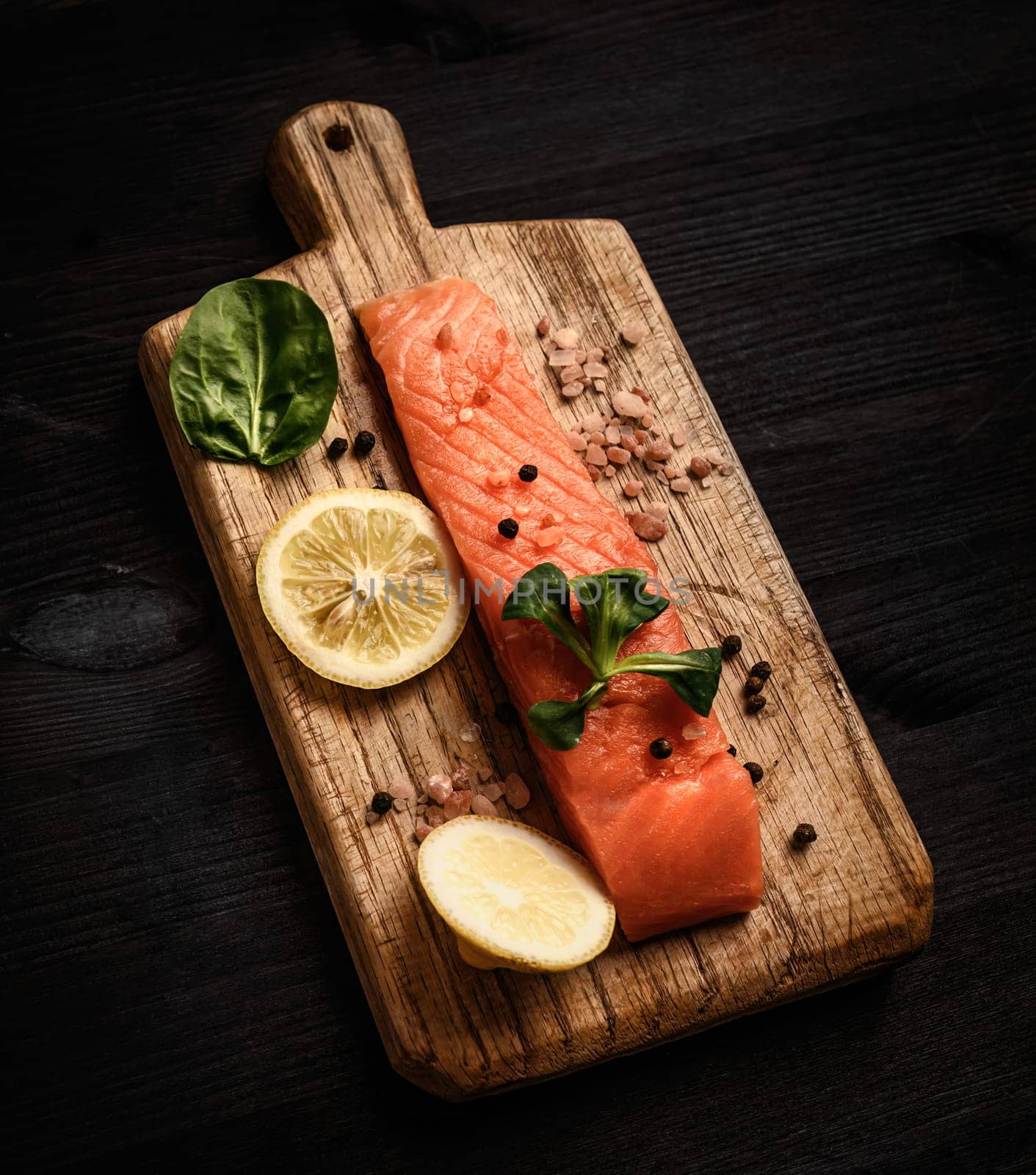 Raw red fish salmon fillet with herbs and lemon on a cutting board ready for cooking healthy dinner