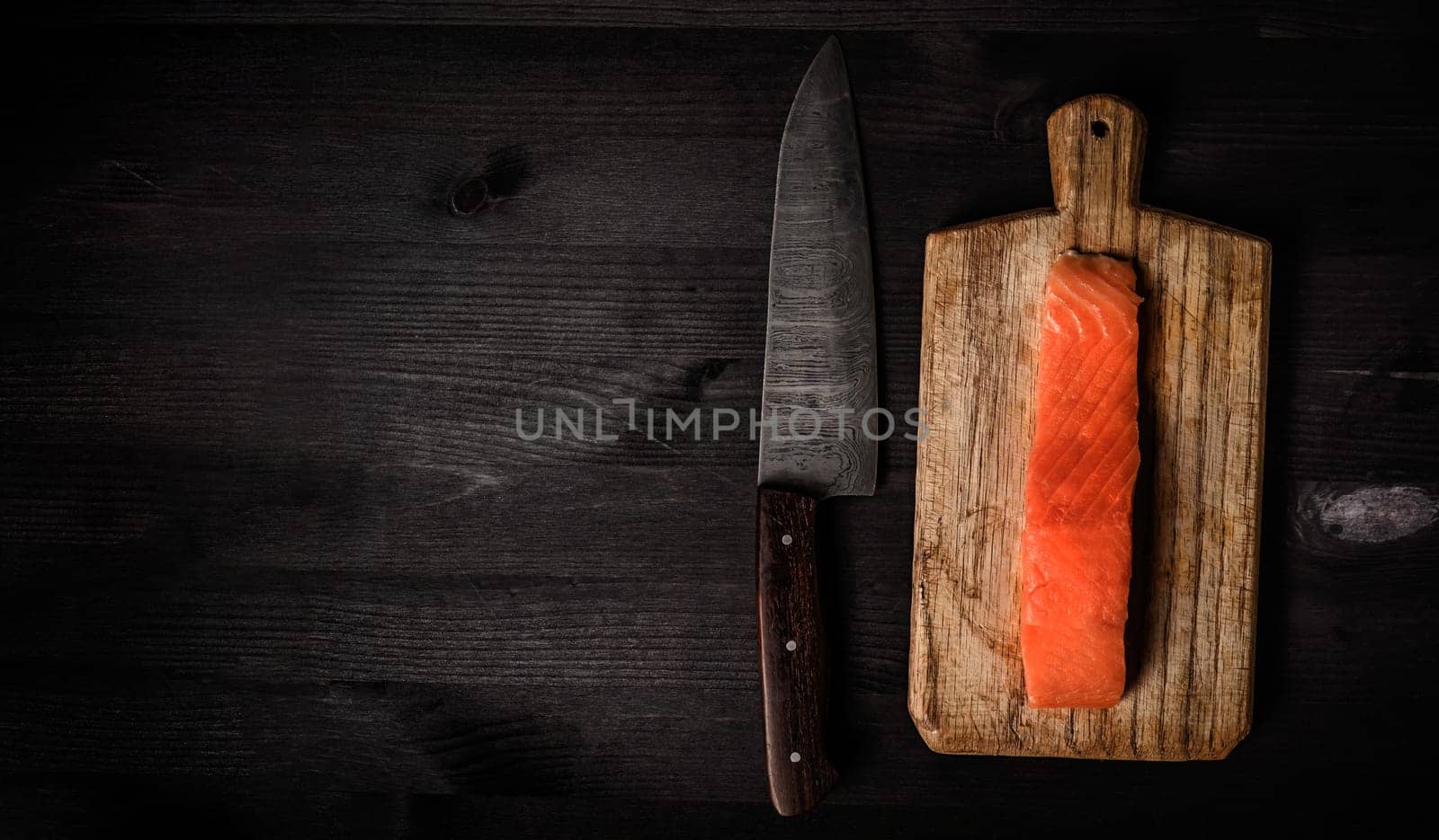 fillet of raw salmon red fish on a cutting board with a big kitchen knife, top view with a copy space