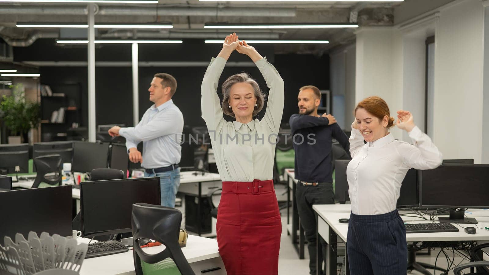 Four office workers warm up during a break. Employees do fitness exercises at the workplace. by mrwed54