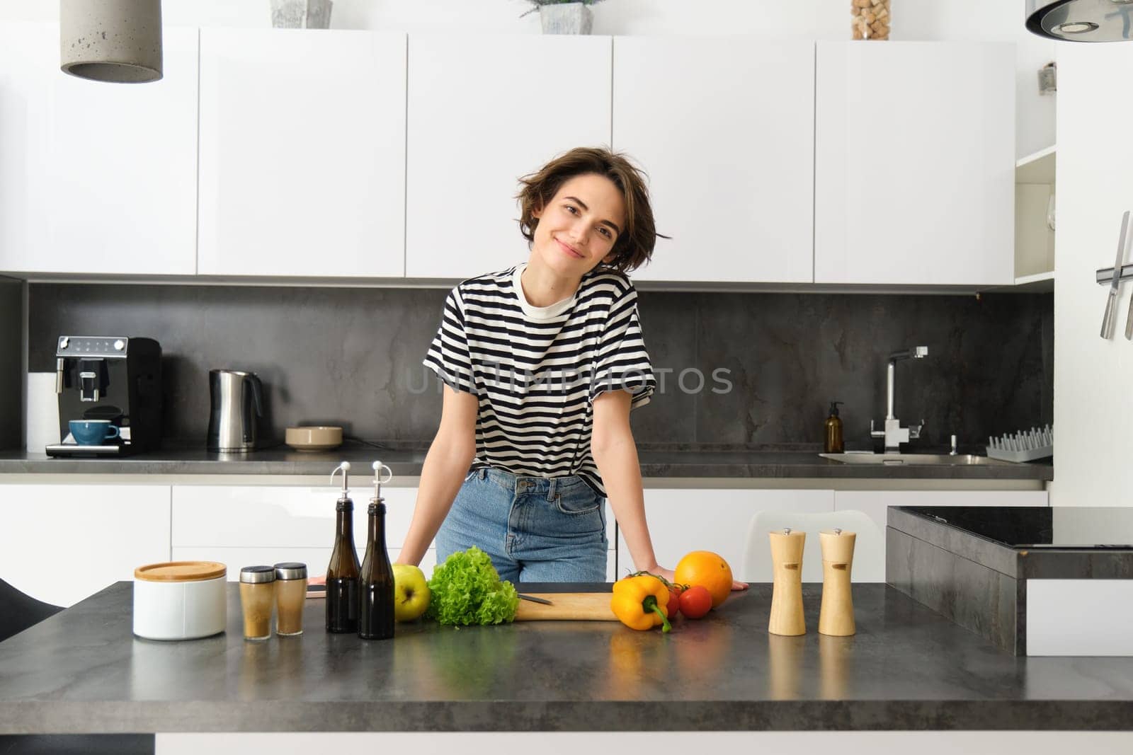 Portrait of young woman cooking salad. Cute girl vegan chopping vegetables on kitchen counter, preparing food.