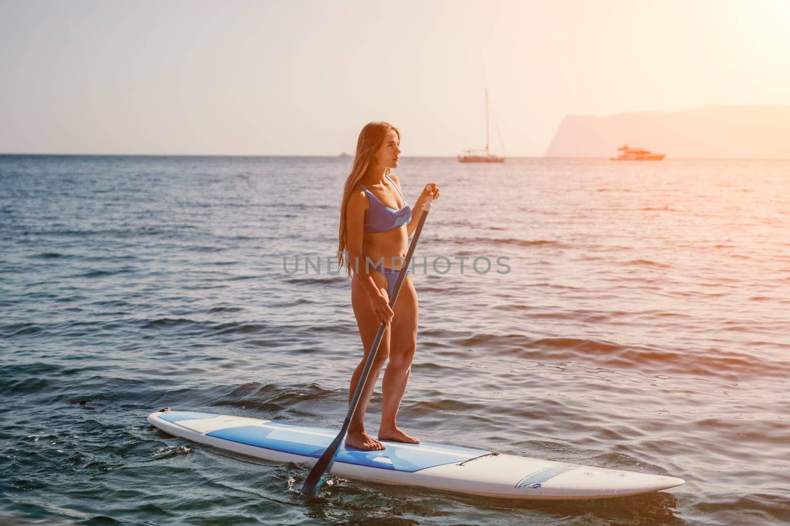 Close up shot of happy young caucasian woman looking at camera and smiling. Cute woman portrait in bikini posing on a volcanic rock high above the sea