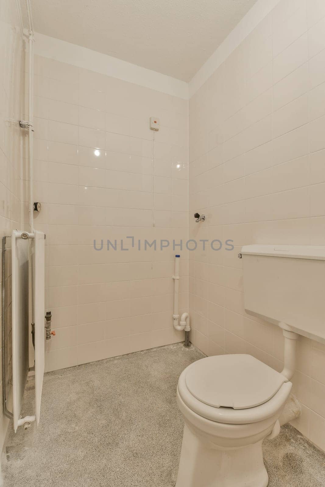 a bathroom with white tiles on the walls, and a toilet in the middle part of the room is empty