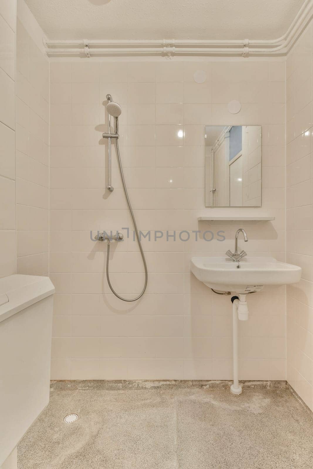 a bathroom with a toilet, sink and shower head mounted on the wall next to a mirror in the corner