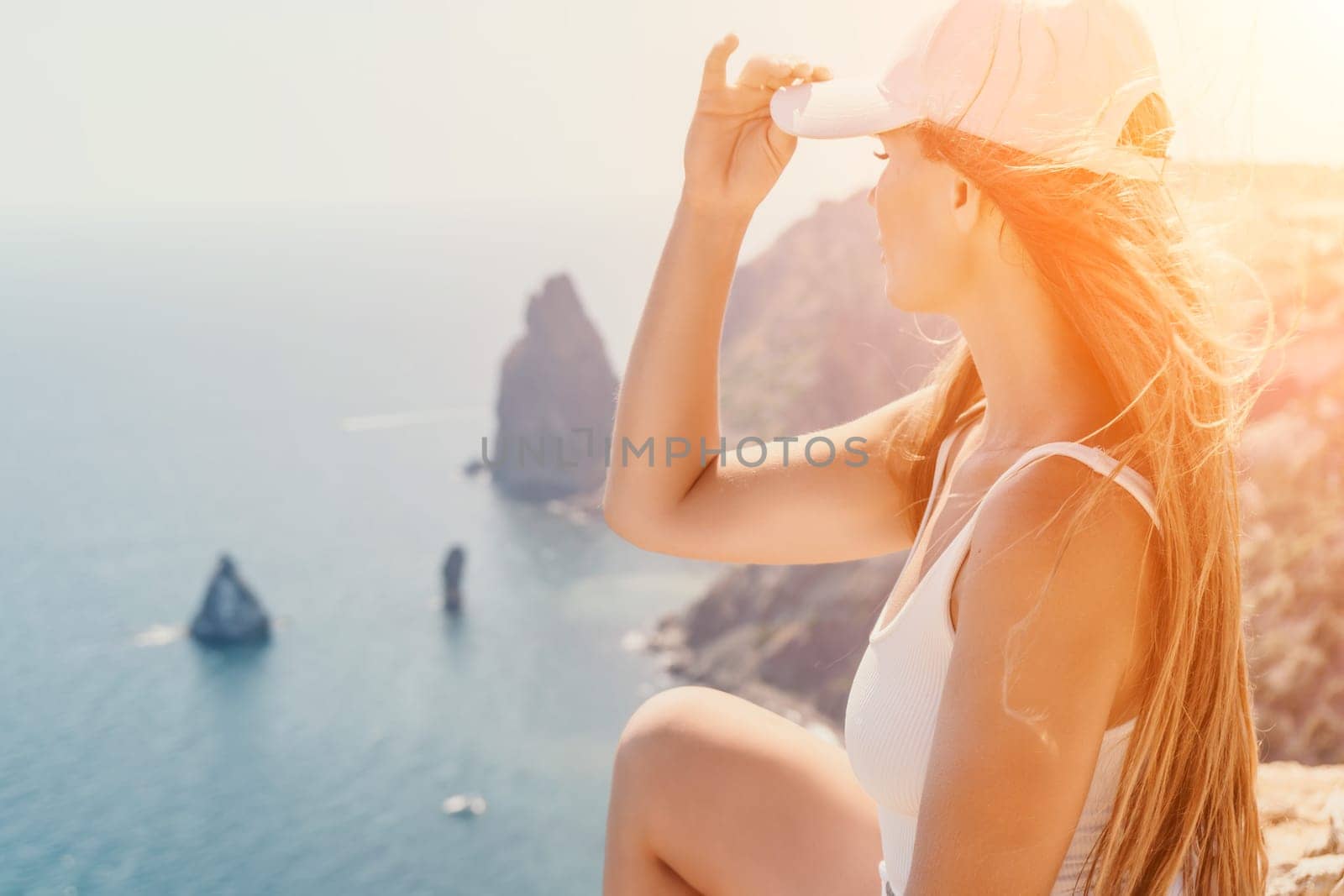 Woman travel sea. Young Happy woman in a long red dress posing on a beach near the sea on background of volcanic rocks, like in Iceland, sharing travel adventure journey