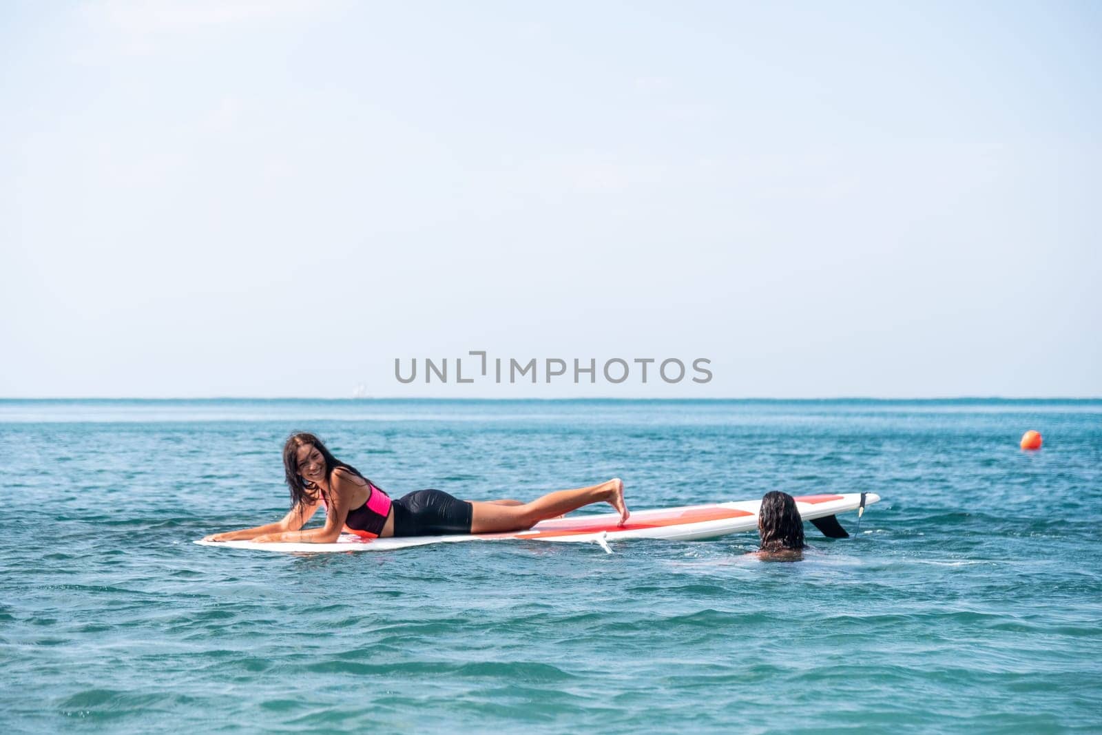 Silhouette of woman standing, surfing on SUP board, confident paddling through water surface. Idyllic sunset or sunrise. Sports active lifestyle at sea or river.