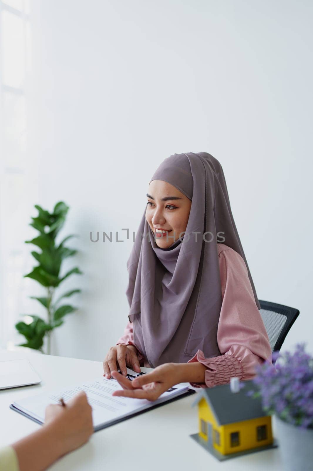 A female Muslim bank employee, making an agreement on a residential loan with a customer