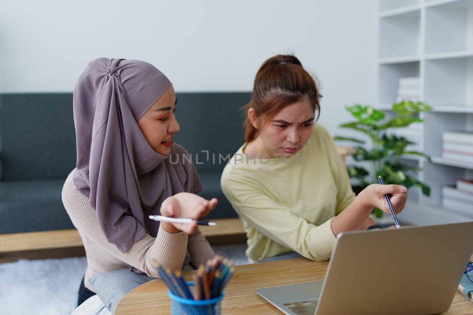 Muslim undergraduates and Asian women are studying online using computers. by Manastrong