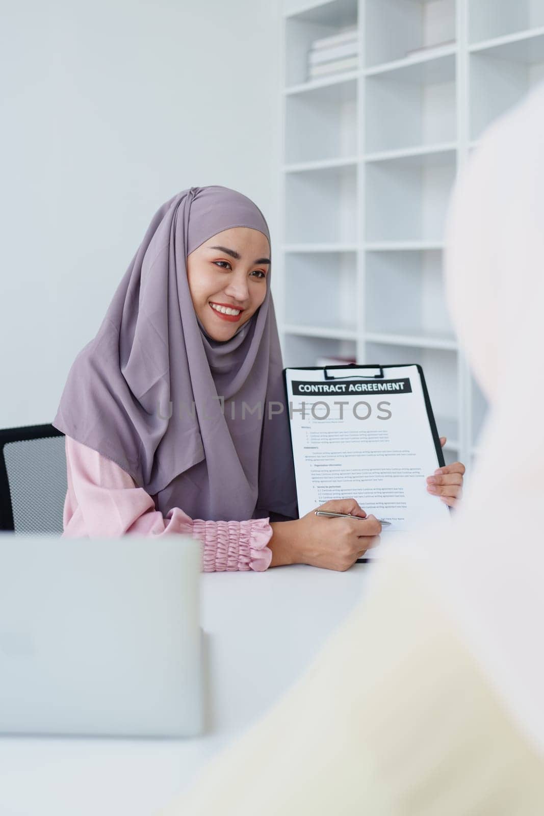 Muslim female employee Hold important documents and discuss agreements with customers. by Manastrong