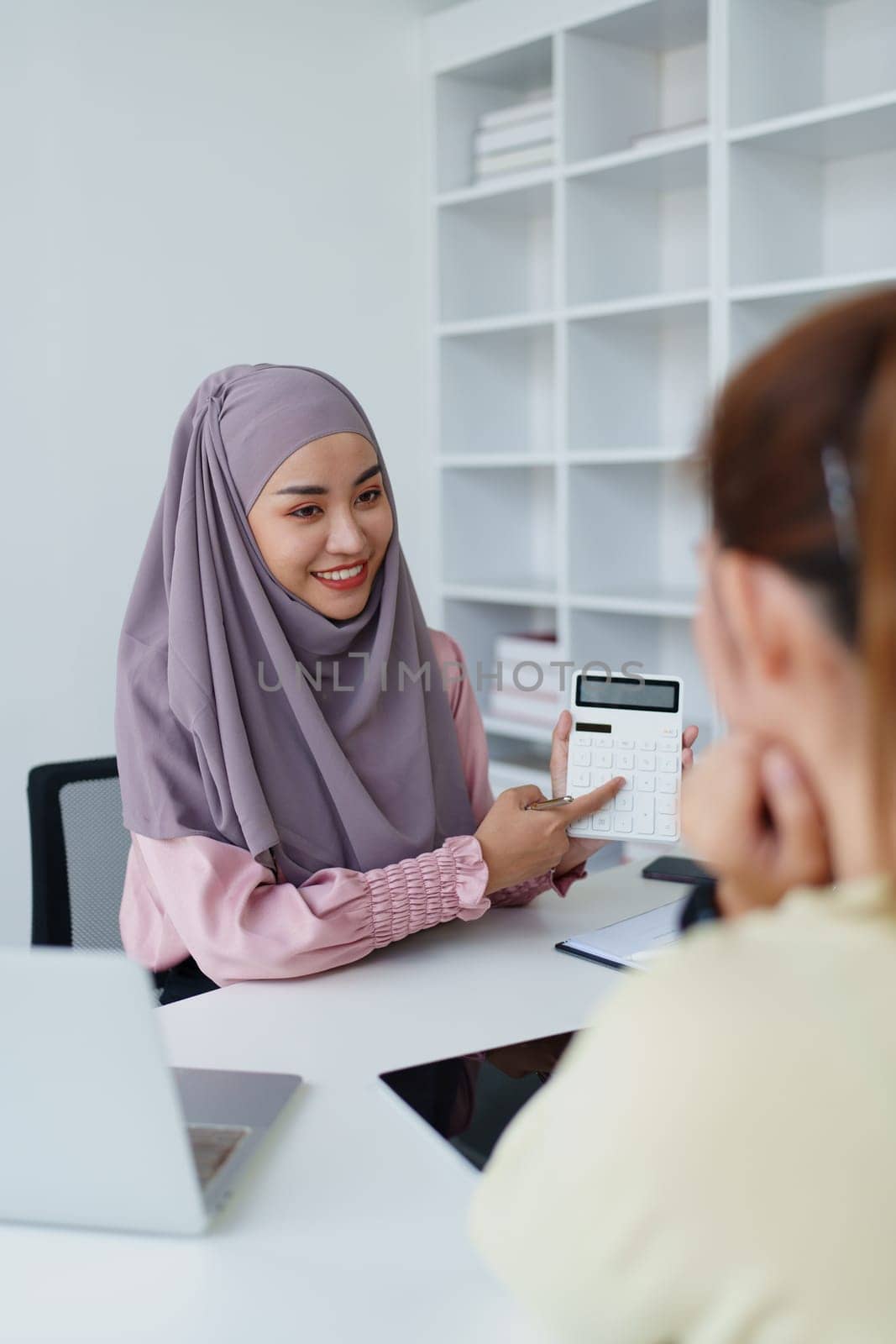 A female Muslim bank employee, making an agreement on a residential loan with a customer