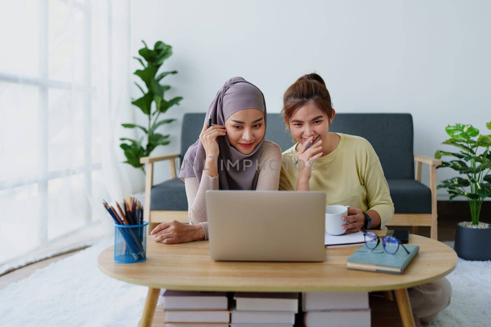 Muslim undergraduates and Asian women are studying online using computers. by Manastrong