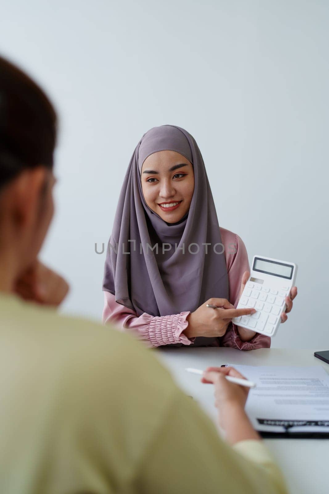 A female Muslim bank employee, making an agreement on a residential loan with a customer