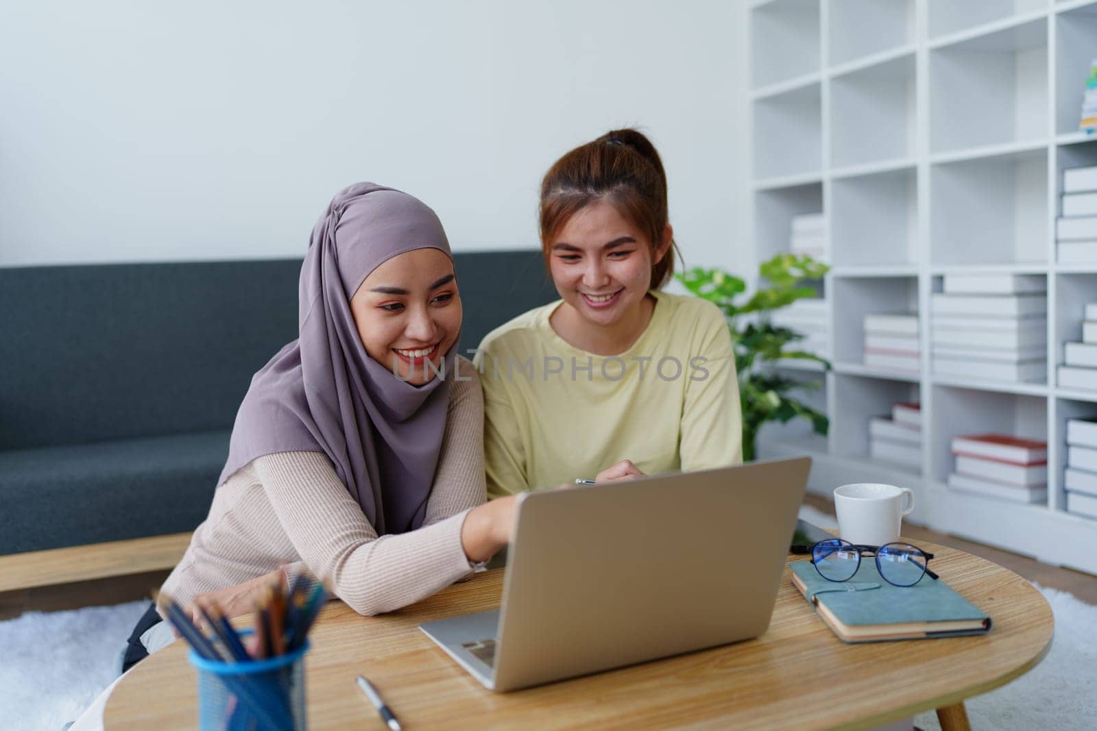 Muslim undergraduates and Asian women are studying online using computers. by Manastrong