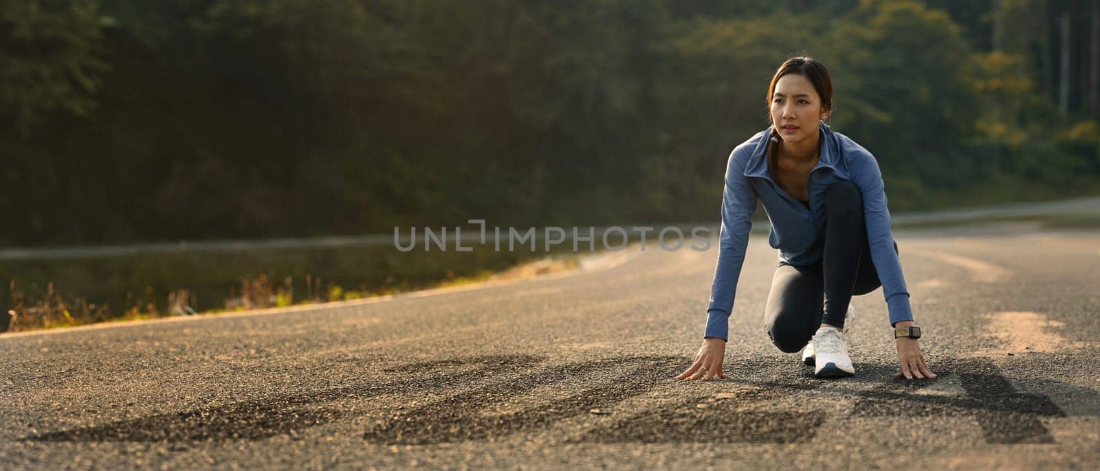 Determined athlete woman in starting position on road with numbers 2024, getting ready for the new year.