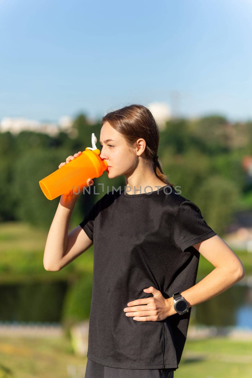 Fit tennage girl runner outdoors holding water bottle. by BY-_-BY