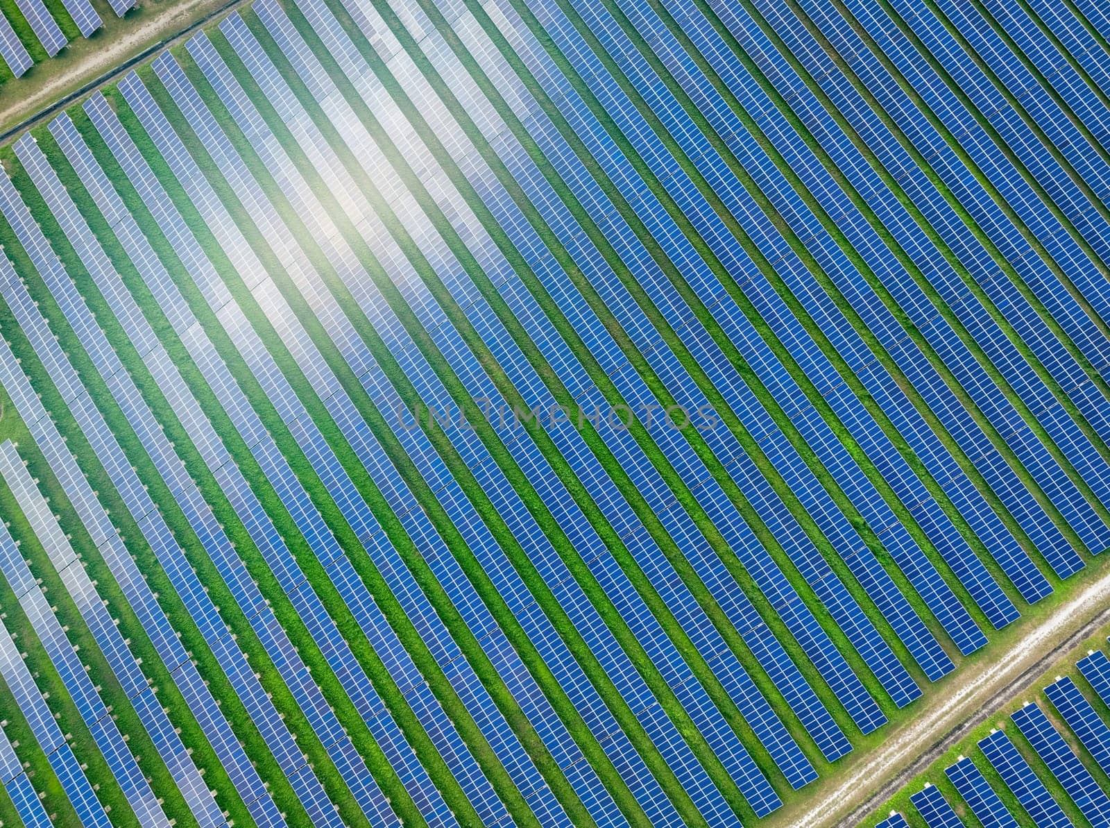 Aerial view of solar farm. Solar power for green energy. Sustainable resources. Solar cell panels use sun light as a source to generate electricity. Photovoltaics or PV. Sustainable renewable energy. by Fahroni