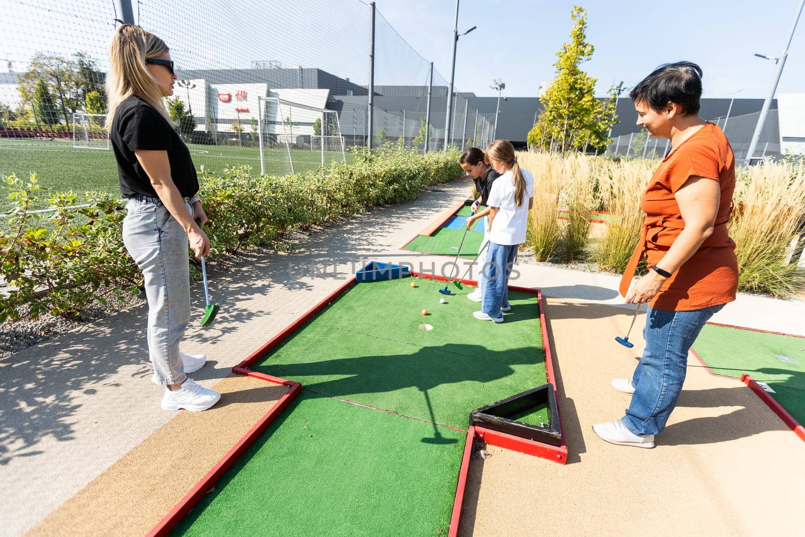 Mother and her little daughter practicing to hit the ball at the course. High quality photo