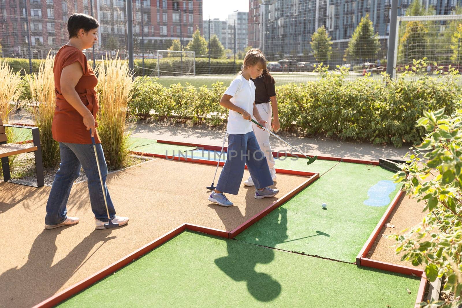 Group of smiling friends enjoying together playing mini golf in the city. by Andelov13