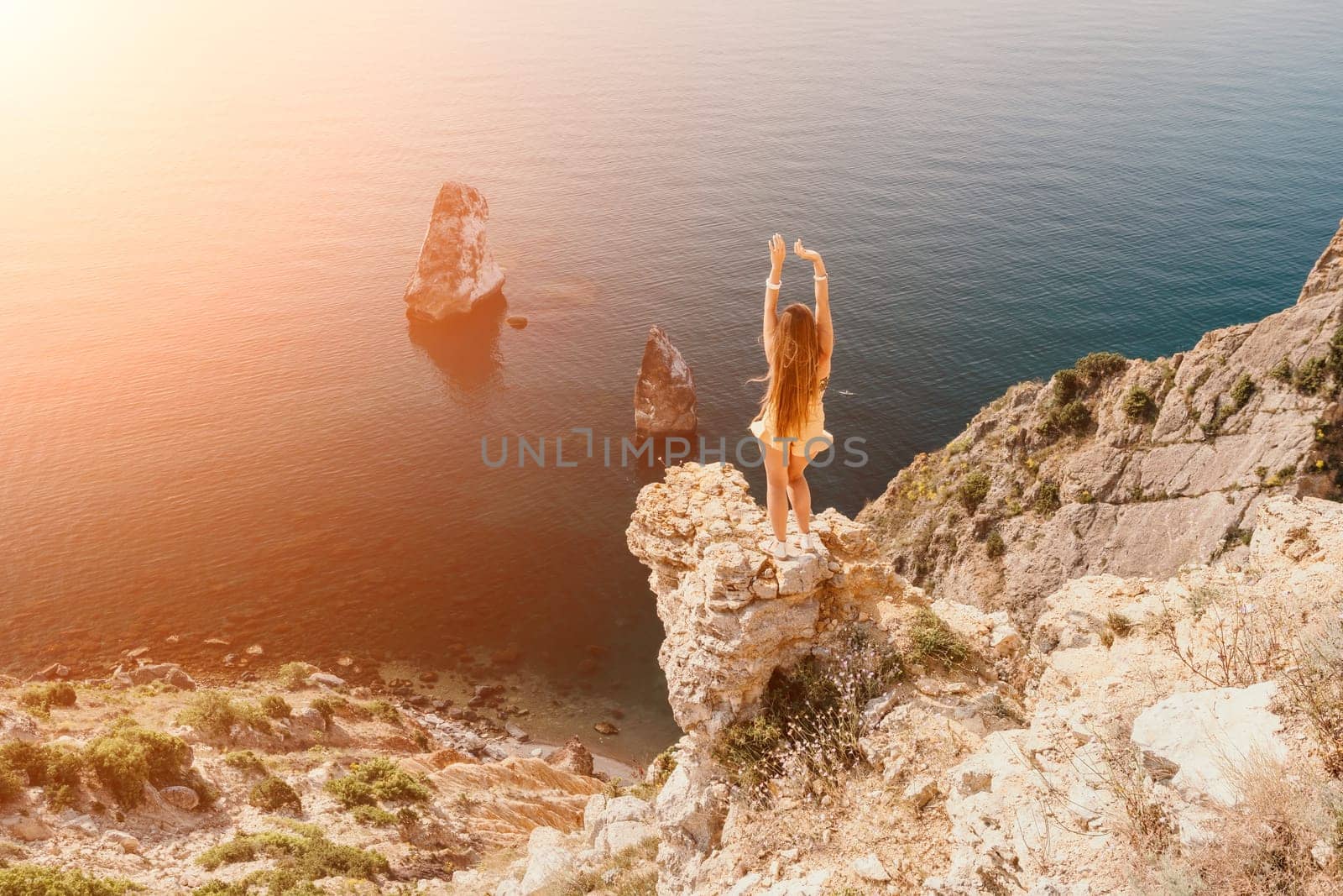 Woman travel sea. Happy tourist taking picture outdoors for memories. Woman traveler looks at the edge of the cliff on the sea bay of mountains, sharing travel adventure journey.