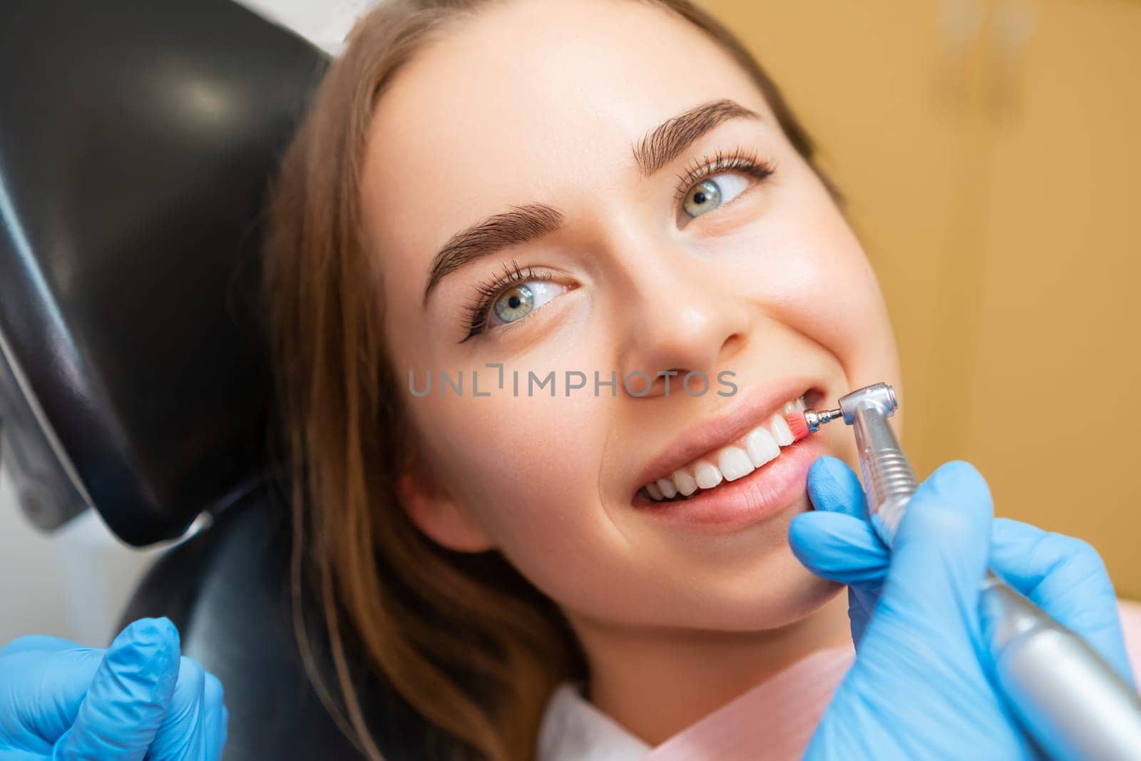 Woman patient sitting in medical chair during teeth grinding procedure.