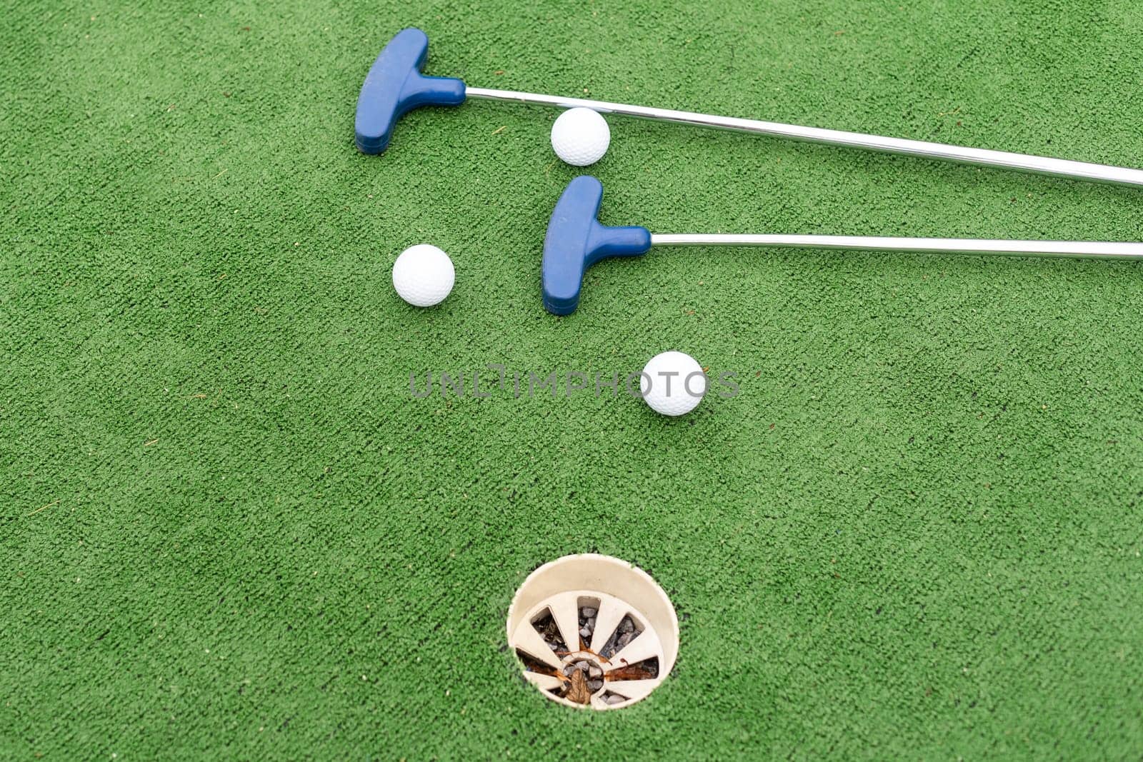 Close-up of miniature golf hole with bat and ball. High quality photo