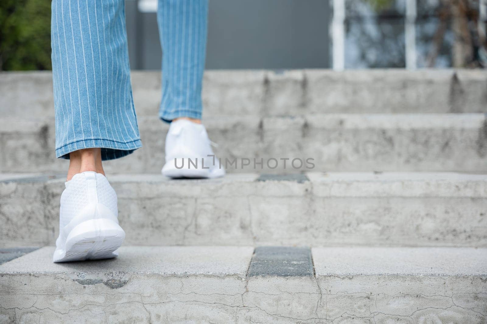 With determination, a woman in sneakers takes on the city stairs, reflecting her relentless progress. Every step symbolizes her commitment to success and ongoing growth. step up by Sorapop