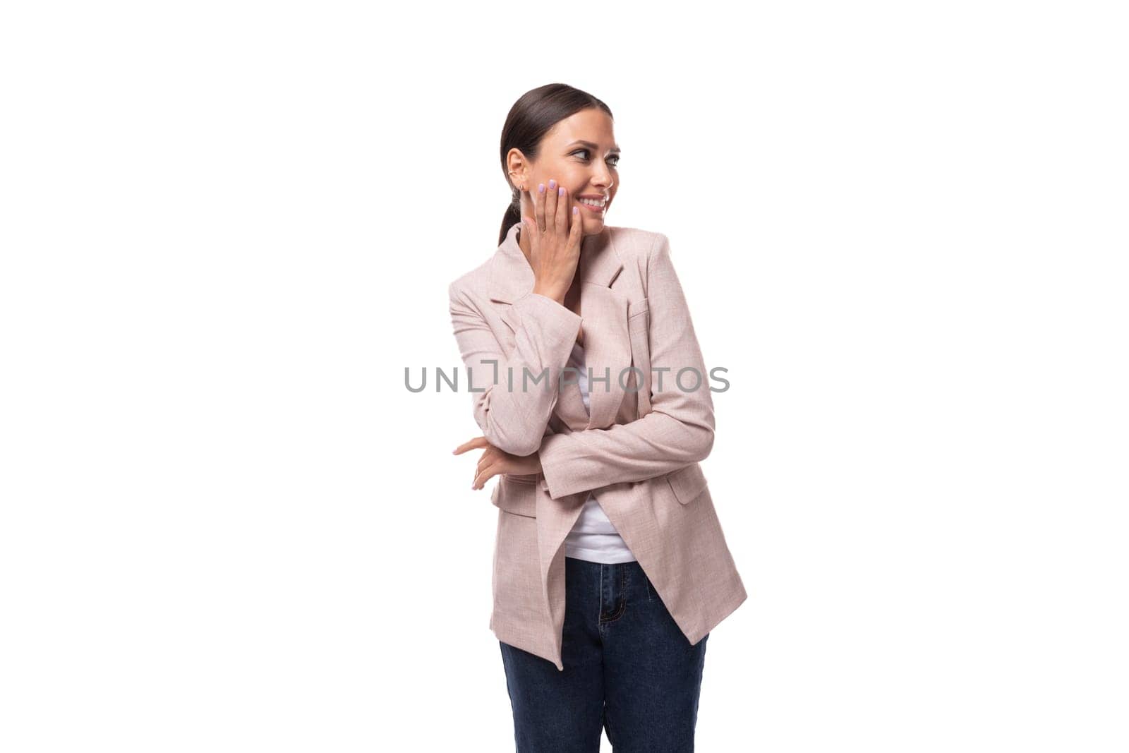 young pleasant brunette woman dressed in a beige jacket smiles and laughs on a white background with copy space.