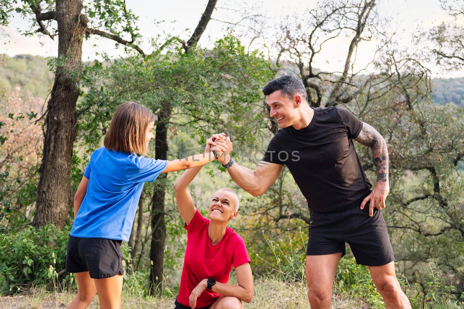 family giving a high five during their training in the woods, concept of sport with children in nature and active lifestyle, copy space for text