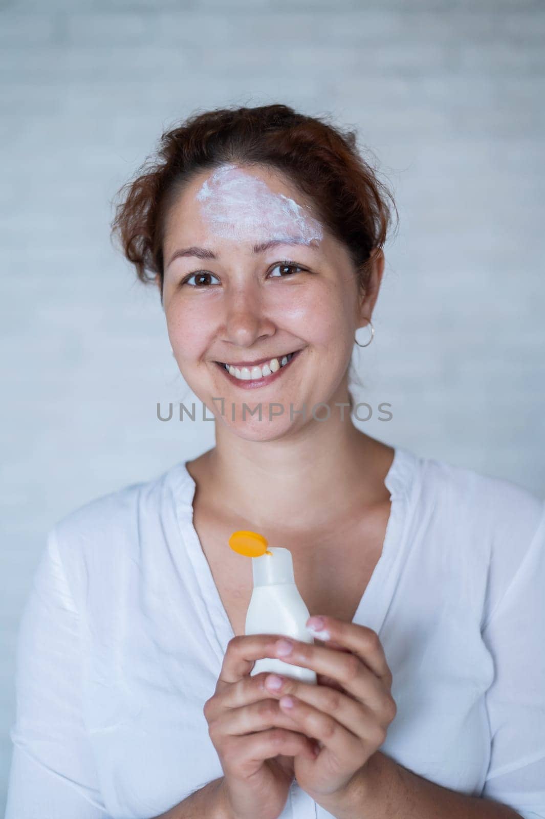 Portrait of a Caucasian woman with vitiligo diseas uses sunscreen.