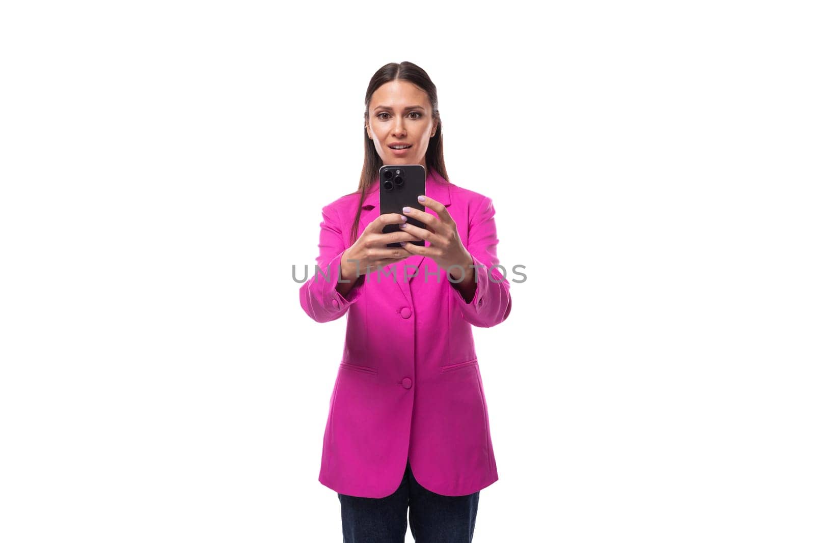 young smart european brunette with black hair dressed in a stylish raspberry jacket is chatting on a smartphone by TRMK