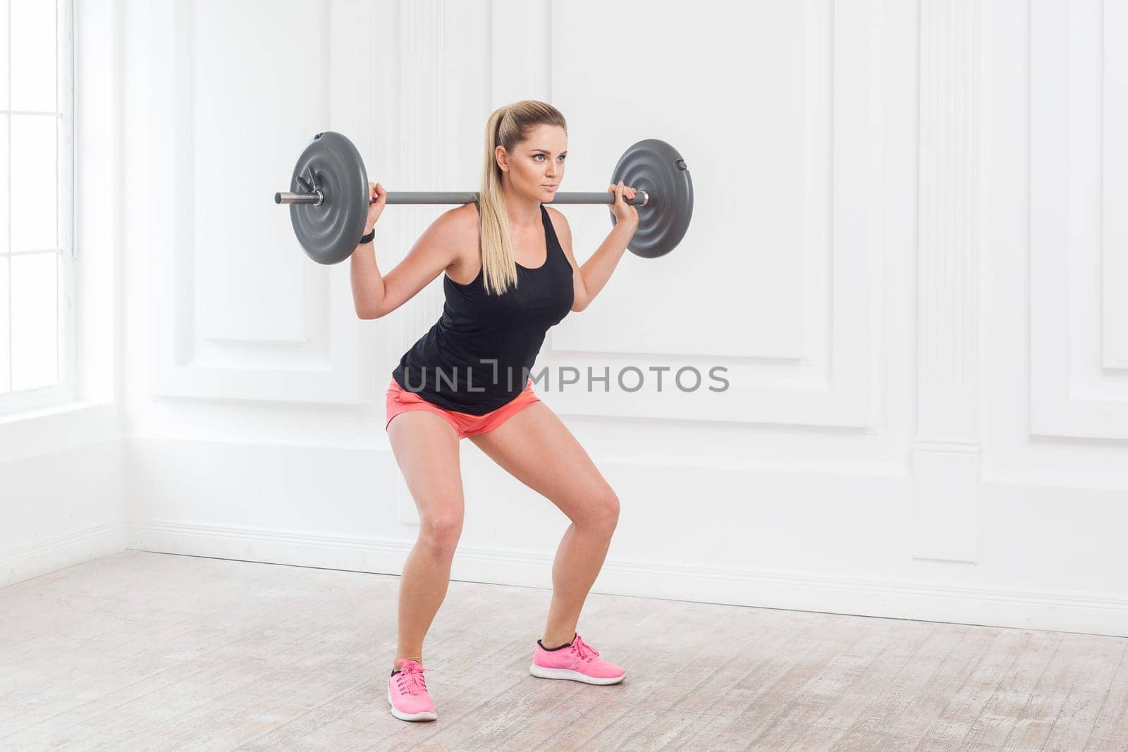 Sporty athletic beautiful woman doing squats and exercising at the gym with the barbell. by Khosro1
