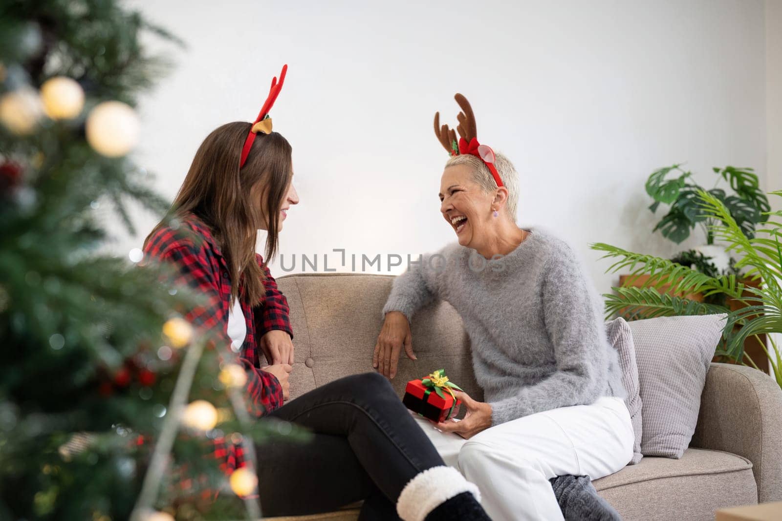 Family winter holiday and concept happy mother and daughter decorate christmas tree and give a gift at home.