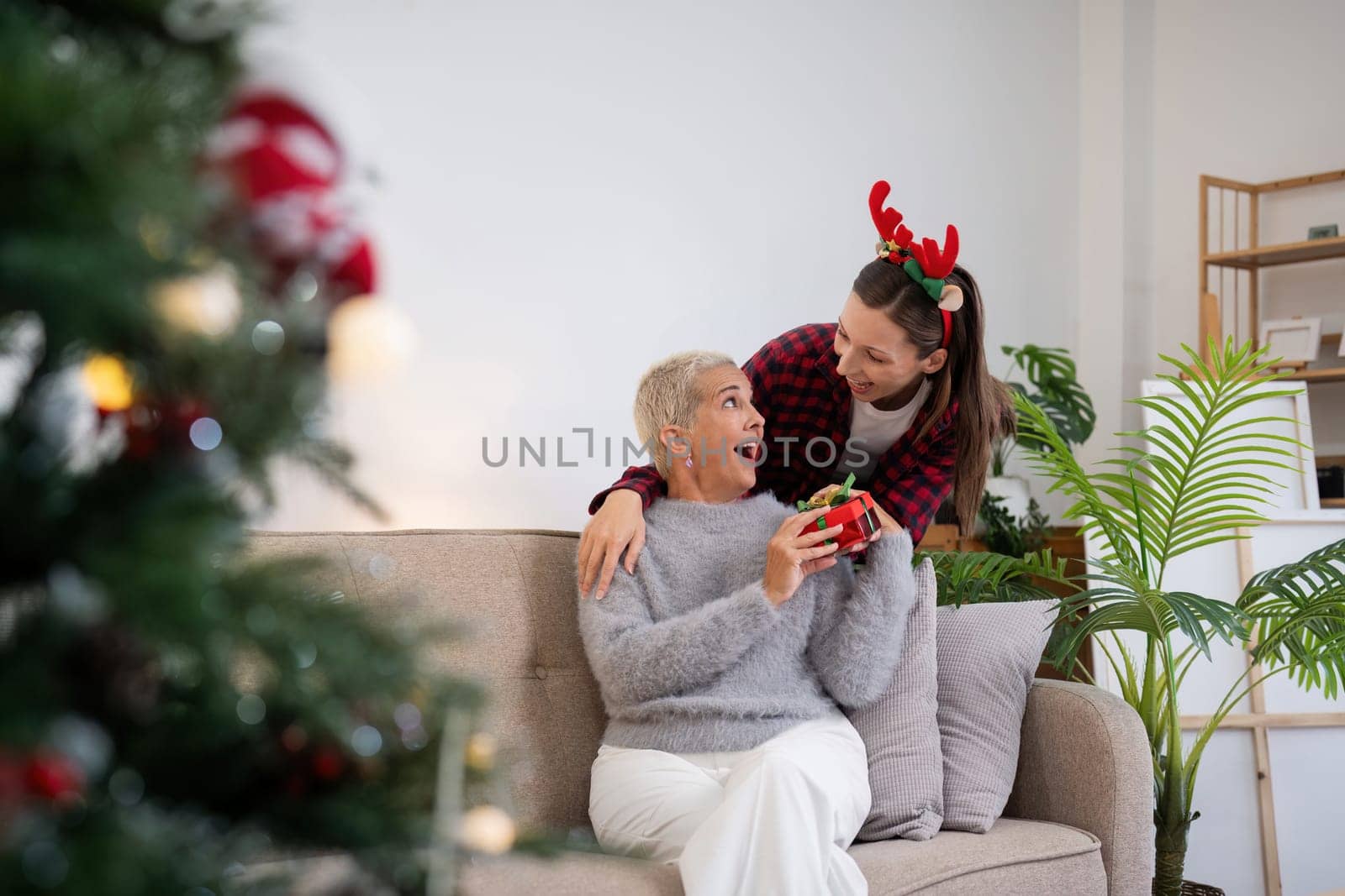 Merry Christmas senior woman with adult daughter exchange gift home.