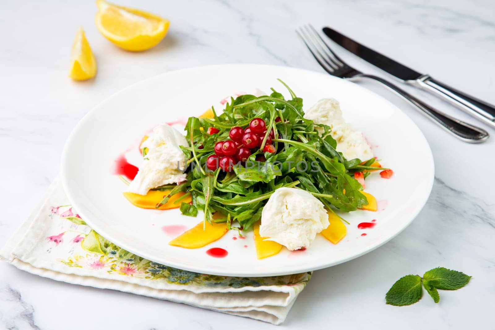 arugula salad with peach slices and red berries on a white plate