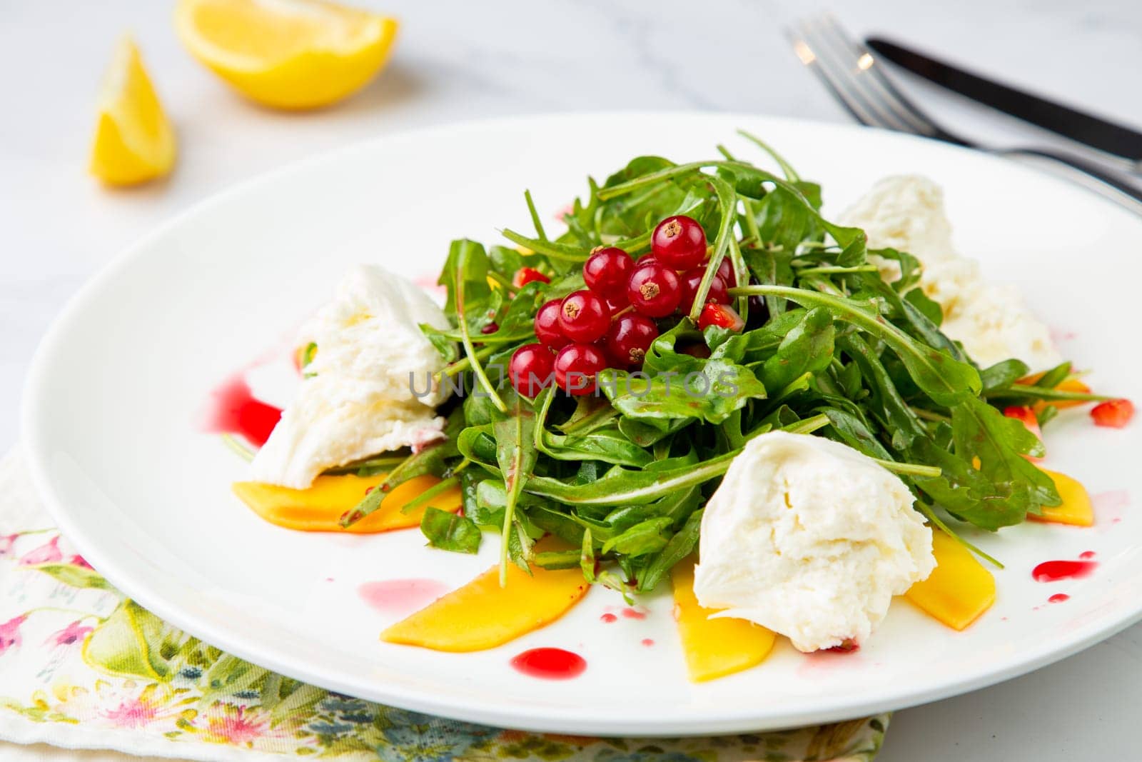 arugula salad with peach slices and red berries on a white plate