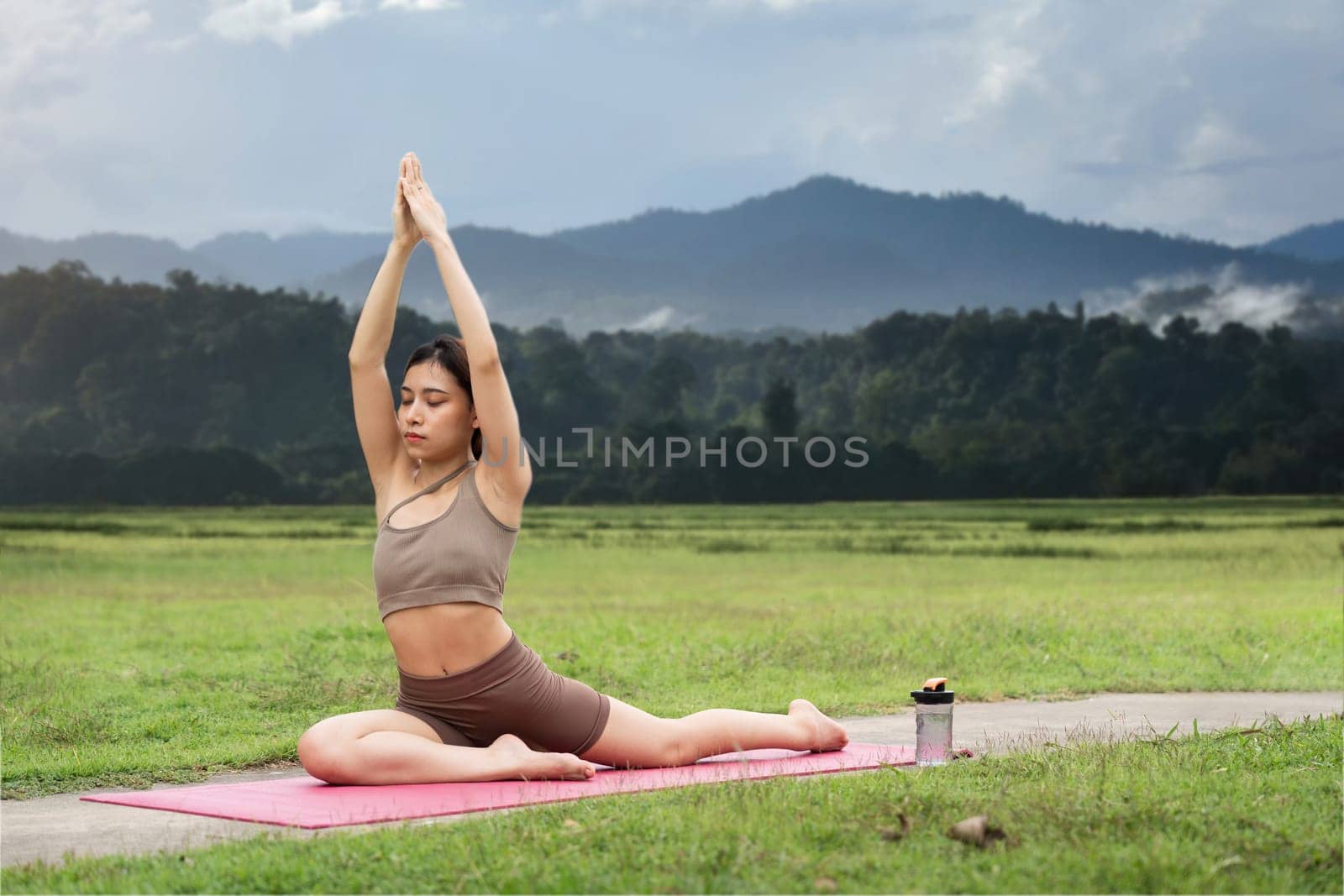 Asian woman sporty practicing yoga at public park outdoor stretching her body. Healthy active lifestyle.