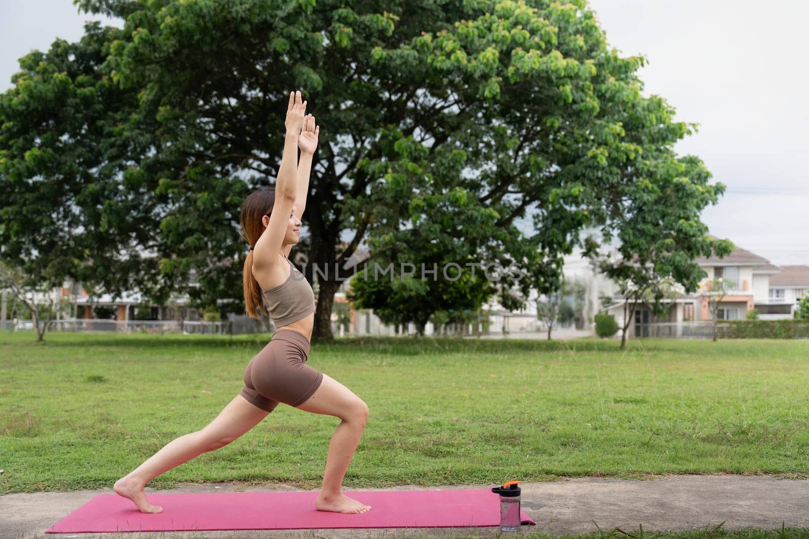 Asian female in sportswear practicing yoga in the park.