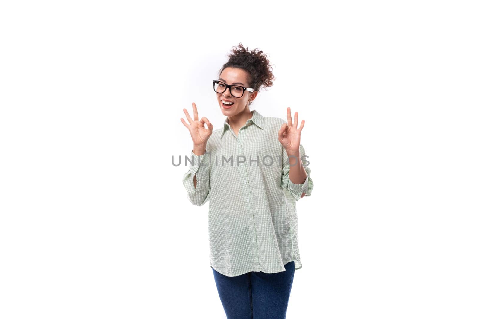 pretty young black-haired curly woman with casual styling bun in shirt feels confident.