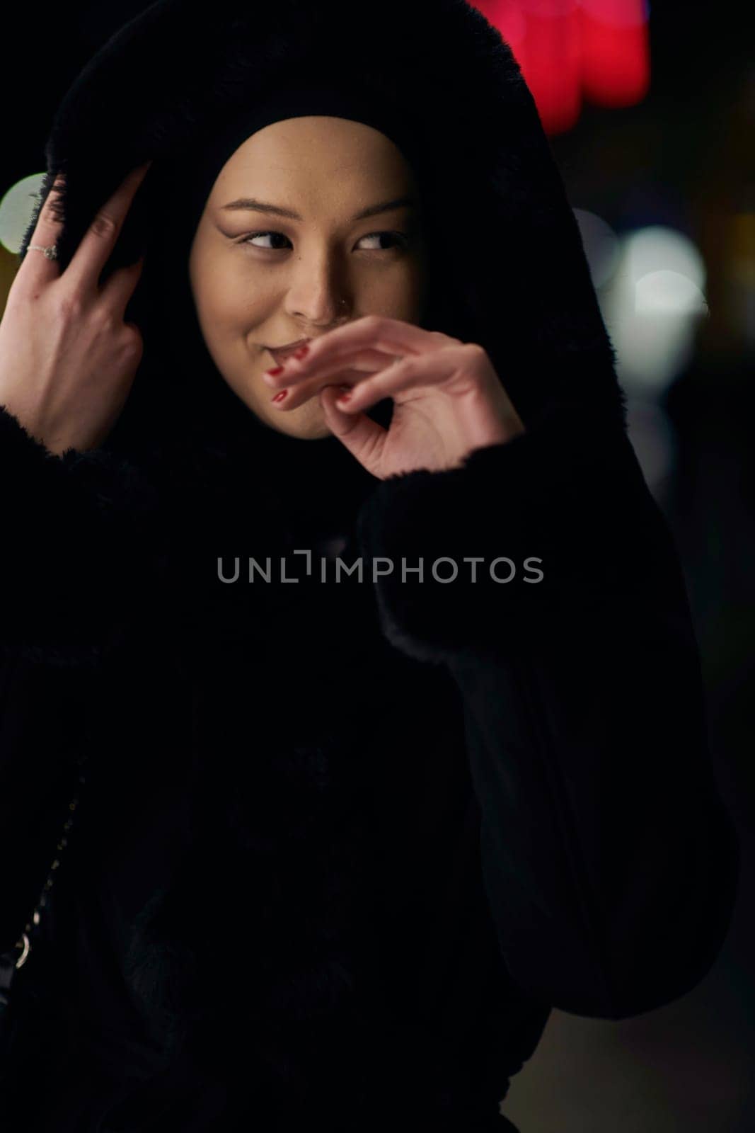 Muslim woman walking on urban city street on a cold winter night wearing hijab by dotshock